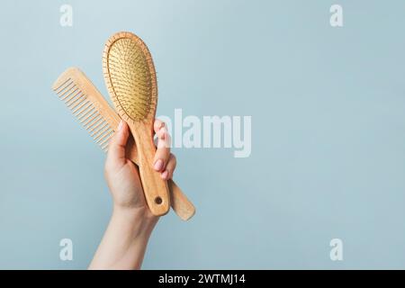Young woman holding wooden hairbrushes on blue background Stock Photo