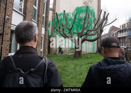 London, UK. 18 Mar 2024. A new mural by street artist Banksy has appeared next to a block of flats in Islington acting as foliage for a tree. The artwork was confirmed by the artist earlier this afternoon as he shared photos on his instagram. Credit: Justin Ng/Alamy Live News Stock Photo