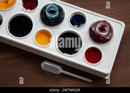 Watercolor paints, painter's pallet and pipette for mixing colors are on the wooden table, close up. Concept of art hobby, creativity Stock Photo