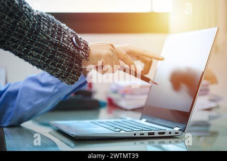 Man and woman pointing fingers at the laptop screen. Business meeting time. Business people meet and discuss with laptop computers at the office. plan Stock Photo