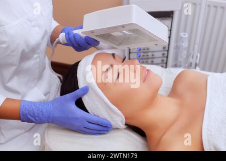 The cosmetologist uses the Wood Lamp for detailed diagnosis of the skin condition. The device detects the presence of skin diseases or inflamed areas. Stock Photo