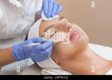 Procedure for cleaning the skin of the face with a steel appliance with a spoon from blackheads and acne. Stock Photo