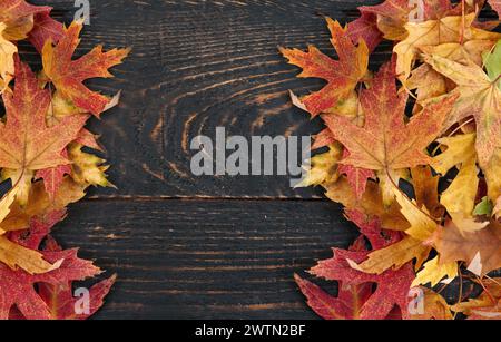 orange autumn fallen leaves on a dark, textured vintage rustic wooden background. View from above. Frame for text. Stock Photo