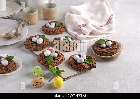Easter chocolate cookies in the shape of Nests with sweet eggs on light table with mint leaves Stock Photo