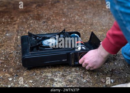 Active lifestyle. A man's hand turns on a portable gas stove. An alternative source for cooking at home during a power outage Stock Photo