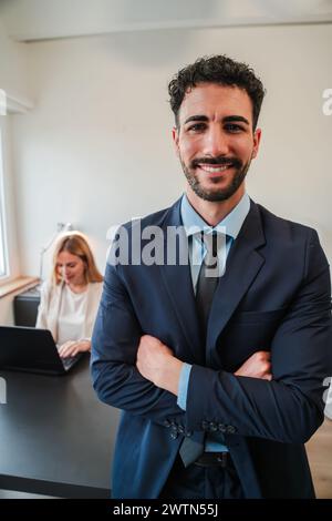 Vertical arms crossed businessman smiling and looking at camera standing at corporate office. Clerk male staring front with confident expression. Positive executive business man with suit at workplace. High quality photo Stock Photo