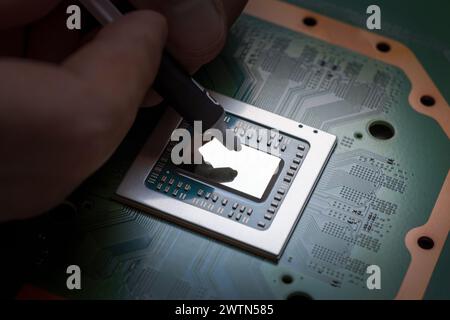 A technician squeezes fresh thermal paste onto the CPU. Central Processing Unit Stock Photo