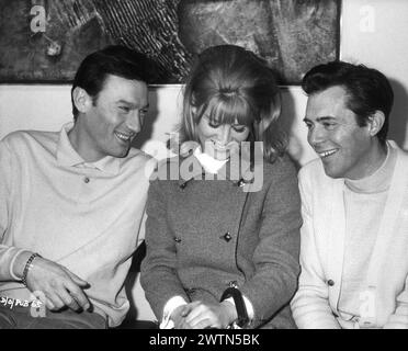 A candid photo of British Actress JULIE CHRISTIE with LAURENCE HARVEY and DIRK BOGARDE on the set of DARLING 1965  Director JOHN SCHLESINGER  Screenplay FREDERIC RAPHAEL Costume Design JULIE HARRIS Music JOHN DANKWORTH Vic-Appia Films / Anglo Amalgamated Stock Photo