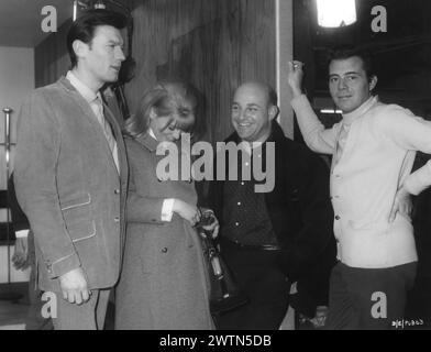 A candid photo of British Actress JULIE CHRISTIE with LAURENCE HARVEY, JOHN SCHLESINGER and DIRK BOGARDE on the set of DARLING 1965  Director JOHN SCHLESINGER  Screenplay FREDERIC RAPHAEL Costume Design JULIE HARRIS Music JOHN DANKWORTH Vic-Appia Films / Anglo Amalgamated Stock Photo