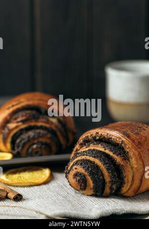 buns with poppy seeds and a cup of coffee on dark wood background. Stock Photo