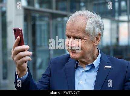 Senior business man looking with a confident smile at his phone. Stock Photo