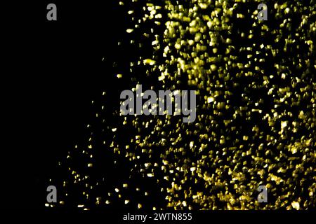 Gold confetti glittering wave. Golden sparkling on black background. Shiny wavy crumbs, golden texture. Stock Photo
