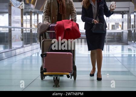 an unrecognizable couple walking with a trolley with suitcases at the airport Stock Photo