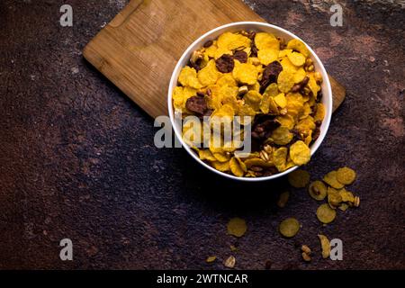 Crispy flakes for breakfast in white bowl on wooden background. Selective focus. Stock Photo
