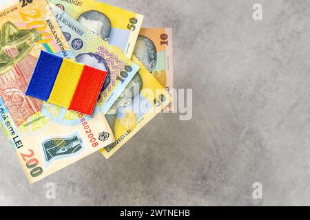 Romania money, gray background, copy space, various Romanian leu banknotes and beautiful embroidered country flag Stock Photo