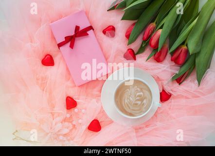 Romantic composition with cup of coffee, spring tulips and trendy gift boxes with ribbon bows on pink background. Stock Photo