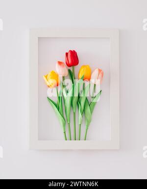 Spring composition made with colorful tulip flowers arranged in frame on white background. Minimal concept and simplicity. Trendy spring flowers idea. Stock Photo