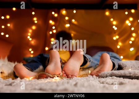 Kids in decorated play tent at home, focus on feet Stock Photo