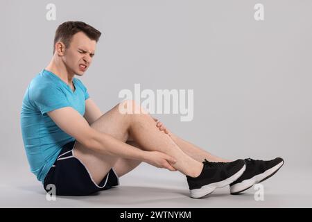 Man suffering from leg pain on grey background Stock Photo