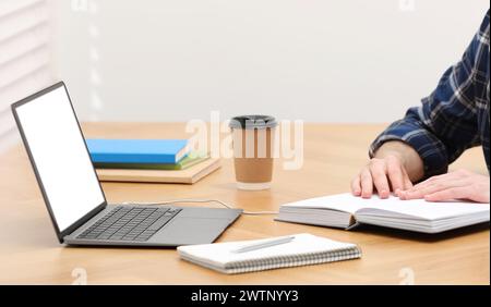 E-learning. Man taking notes during online lesson on table indoors, closeup Stock Photo