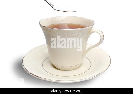 Adding a teaspoon of sugar to a cup of tea on a white background. Stock Photo