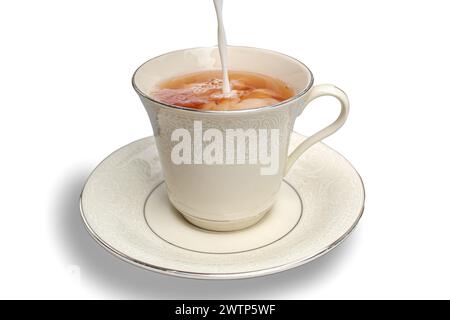 Milk being poured into cup of tea on white background Stock Photo