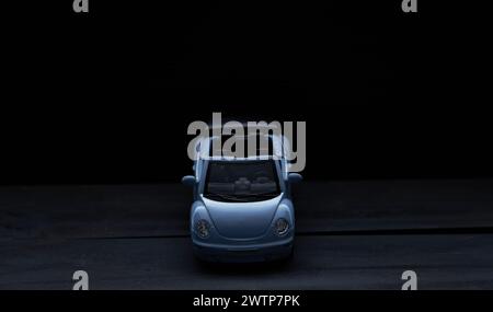 miniature blue car on a dark background in the photo at a slight angle from the top of the front Stock Photo