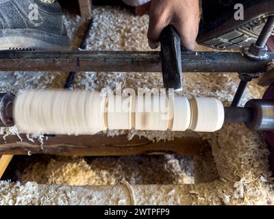 Turner working on a lathe in the workshop curving woods Stock Photo