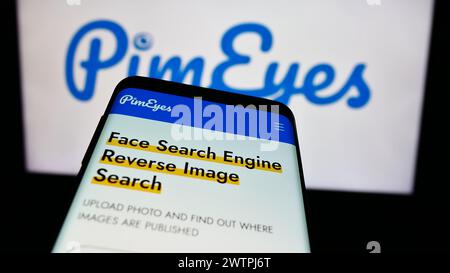Mobile phone with website of facial recognition search company PimEyes in front of business logo. Focus on top-left of phone display. Stock Photo
