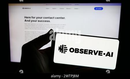 Person holding smartphone with logo of artificial intelligence contact center company Observe.AI in front of website. Focus on phone display. Stock Photo