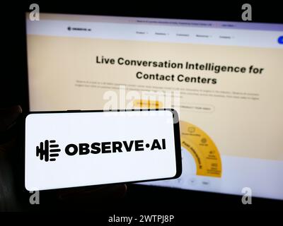 Person holding mobile phone with logo of artificial intelligence contact center company Observe.AI in front of web page. Focus on phone display. Stock Photo