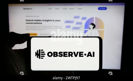 Person holding cellphone with logo of US artificial intelligence contact center company Observe.AI in front of webpage. Focus on phone display. Stock Photo