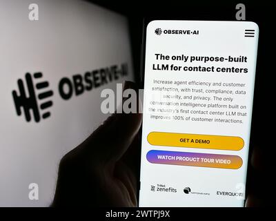 Person holding smartphone with webpage of artificial intelligence contact center company Observe.AI with logo. Focus on center of phone display. Stock Photo