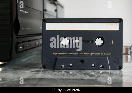 Front view of audio cassette with empty space for notes standing in front of cassette deck on polished marble shelf with reflection Stock Photo