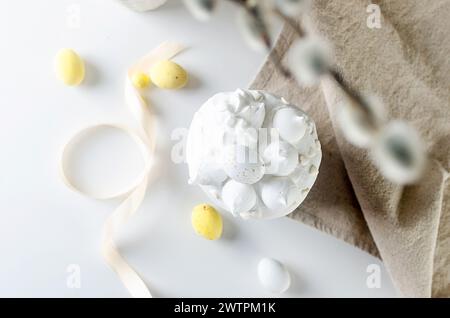 Place setting for Easter dinner on the white table with Easter cake with colorful topping, Decorative chocolate eggs sweets, willow and holiday decora Stock Photo