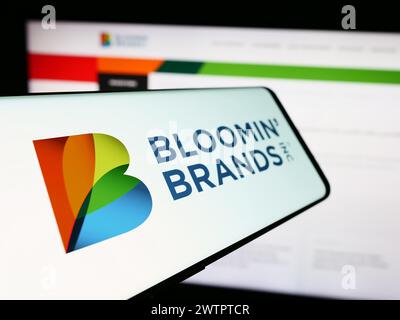 Smartphone with logo of American restaurant holding company Bloomin' Brands Inc. in front of business website. Focus on left of phone display. Stock Photo