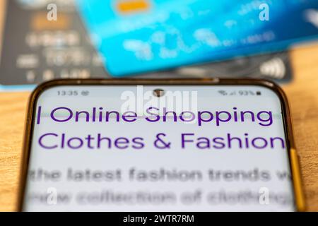 A close up of a smart phone with the words online shopping, clothes and fashion and bank card. An online shopping concept Stock Photo