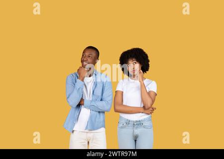 Two young African American individuals lean on their hands with thoughtful expressions Stock Photo