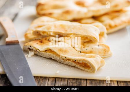 Freshly Baked Naan Bread on cutting board on a wooden table Stock Photo