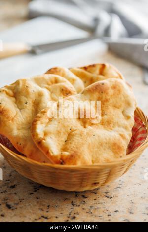 Freshly Baked Naan Bread in basket on a kitchen table. Stock Photo