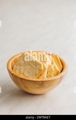 Golden Baked Crackers in wooden bowl on a White kitchen table. Stock Photo