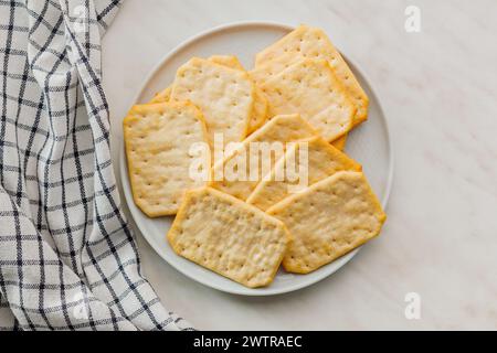 Golden Baked Crackers on the  plate on a White kitchen table. Top view. Stock Photo