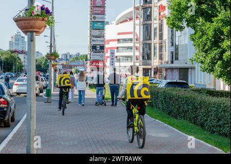 Saransk, Mordovia, Russia. June 4, 2023. Yandex Market deliverers are walking with stalls on bicycles along the city street. Delivery of food and shop Stock Photo