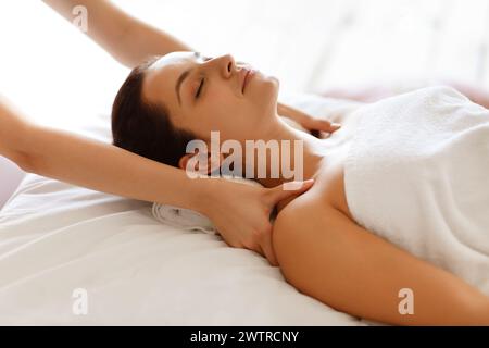 therapist rubbing sleeping woman's shoulders making relaxing body massage indoor Stock Photo