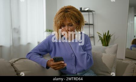 Shocked African American ethnic female looking at cellphone read unbelievable astonish news girl woman wonder with mobile phone shock bad sms Stock Photo