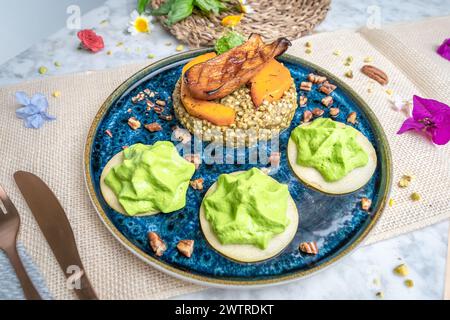 A bowl of food placed on a table with silverware and flowers Stock Photo