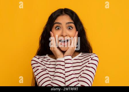 Young woman surprised expression on yellow Stock Photo