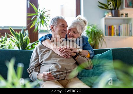 Portrait of a happy senior couple sitting on sofa at home Stock Photo