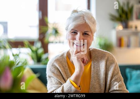 Mature woman looking at camera and smiling in her living room at home Stock Photo
