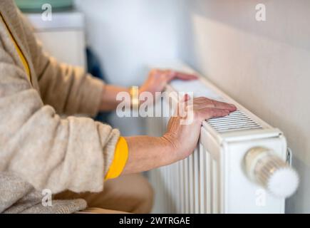 Senior woman checking heating radiator in her apartment Stock Photo